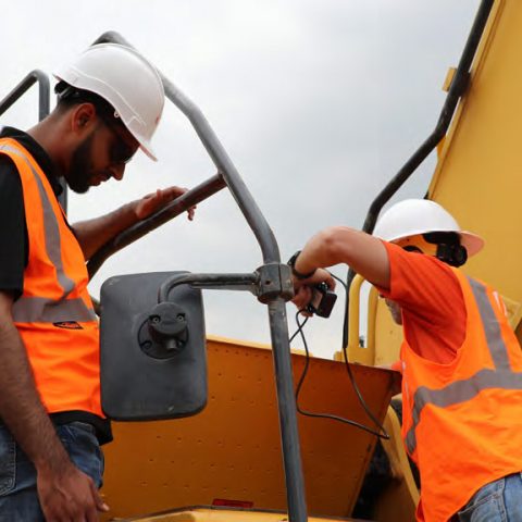 Mechanics Installing Equipment Share Trackers on Heavy Construction Equipment